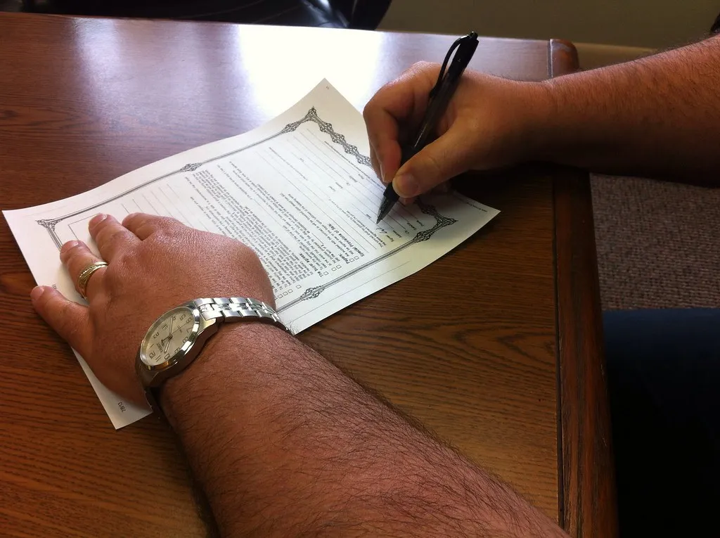 A Georgetown homeowner signing a written lawn care quote at a kitchen table.